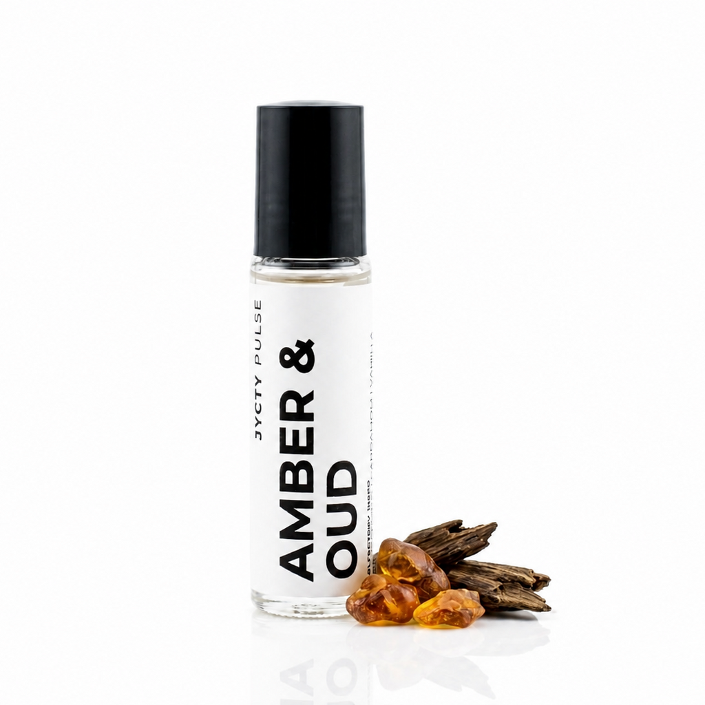 A clear glass roller bottle with a black cap and a white label reading 'AMBER & OUD' and 'JYCTY PULSE', shown on a white background with amber pieces and dried botanicals beside it.