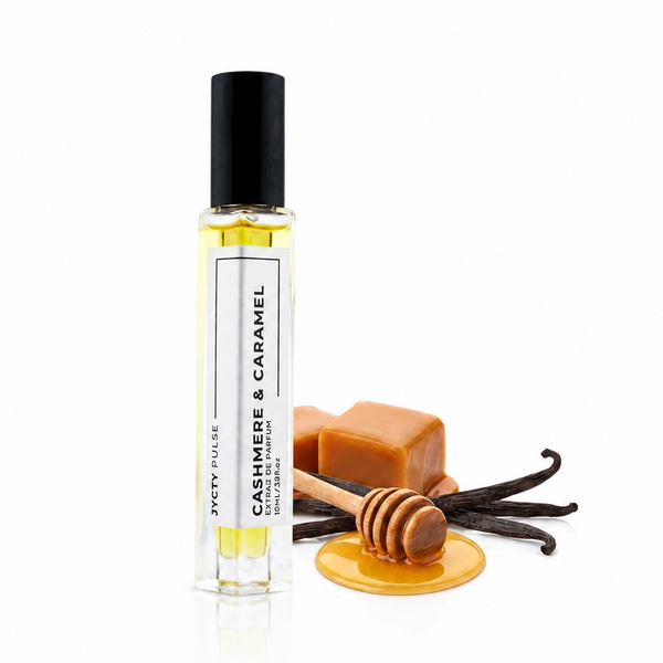 A clear 10ML glass perfume SPRAY bottle with a black cap, labeled 'CASHMERE & CARAMEL' by SCOTCH SCALPERS, standing next to caramel pieces, vanilla beans, and a honey dipper on a white background.