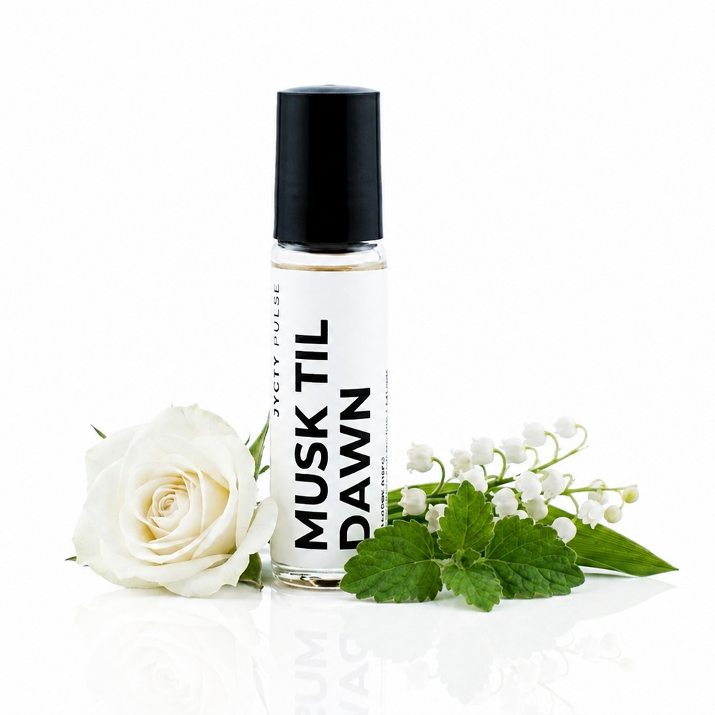 A clear cylindrical roller bottle with a black cap and white label reading 'MUSK TIL DAWN' in black text, styled with a white rose and green leaves on a clean white background.