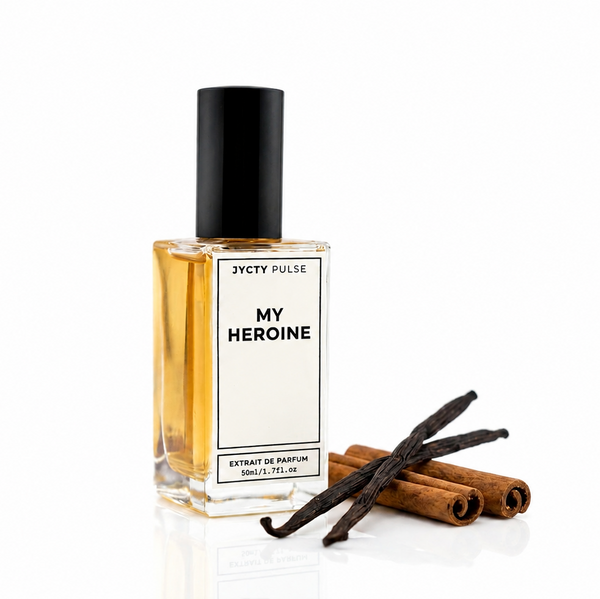 A bottle of JYCTY Pulse My Heroine extract de parfum with a black cap and white label, shown next to vanilla beans and cinnamon sticks on a white reflective surface.