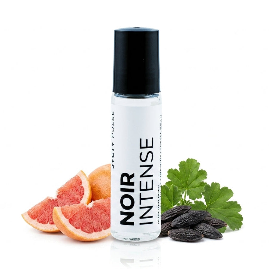 A clear cylindrical bottle with a black cap labeled 'NOIR INTENSE' stands on a white background, styled with grapefruit slices, green leaves, and dark seeds.
