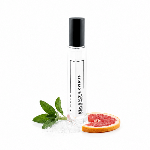 A clear glass roller bottle with a black cap labeled 'SEA SALT & CITRUS' by JYCTY, styled with green leaves and a grapefruit slice on a white background.