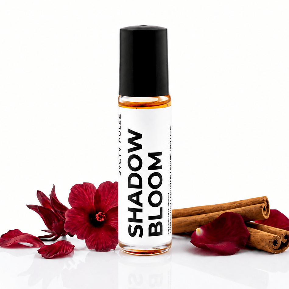 A clear glass roller bottle with a black cap and a white label reading 'SHADOW BLOOM' by JYCTY, styled with red flower petals and cinnamon sticks on a white background.