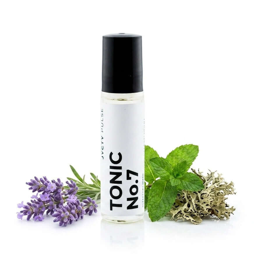A clear cylindrical roll-on bottle labeled 'TONIC No.7' with a black cap, styled with lavender flowers, green mint leaves, and dried herbs on a white background.
